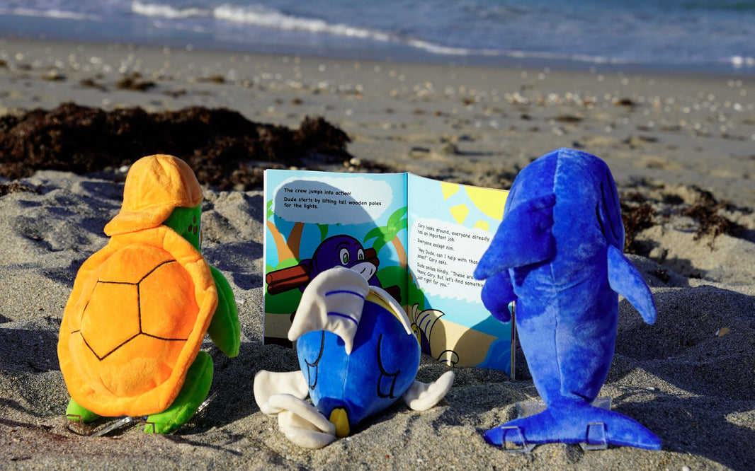 Three plush friends reading a storybook together facing the sea